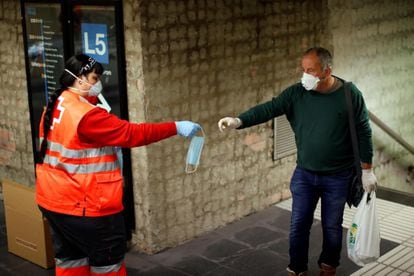 A Red Cross volunteer hands out masks in a Metro station in Barcelona on Tuesday.