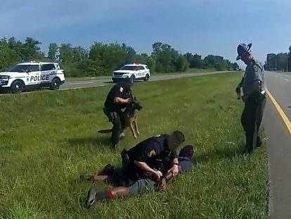 Truck driver Jadarrius Rose is handcuffed by an Ohio State Highway Patrol officer as a police dog is held back after Rose was attacked by the animal during a traffic stop south of Columbus, Ohio, on July 4, 2023.