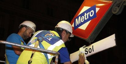 Workers replacing signage at Sol Metro station.