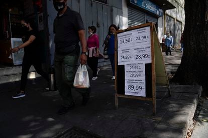 People walk past a price list marked in bolívars in Caracas, Venezuela.
