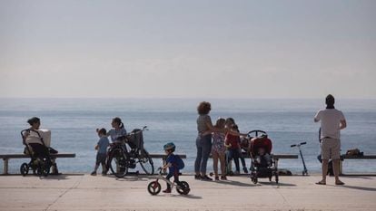 Families enjoy the seaside promenade in Barcelona on Sunday.