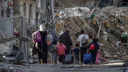 Evacuating residents pass a destroyed building following Israeli air strikes in the northern Gaza Strip, 07 November 2023