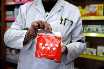 A pharmacist holds one of the free masks that will be handed out in the Madrid region.