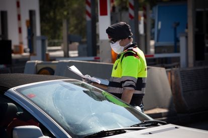 A Catalan regional police officer asks a driver to justify his trip at a toll plaza in La Roca del Vallès on Thursday, at the start of the Easter holiday. 
09/04/2020