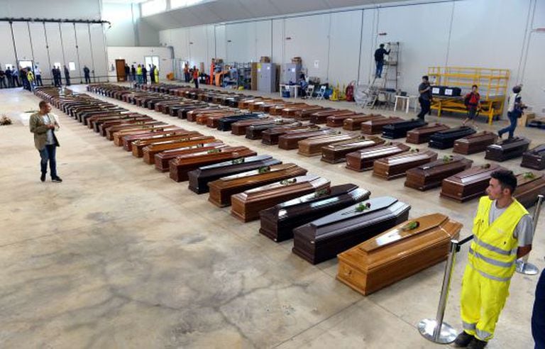 Coffins of dead migrants are lined up in a hangar of Lampedusa airport.