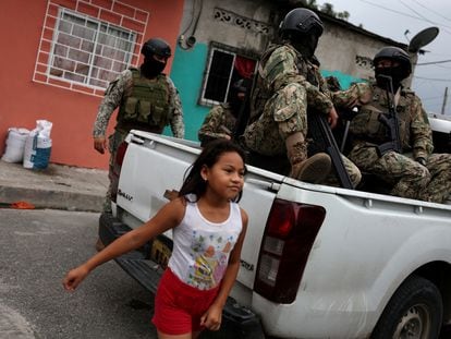 A girl walks past Ecuadorian military personnel in the city of Guayaquil, Ecuador.