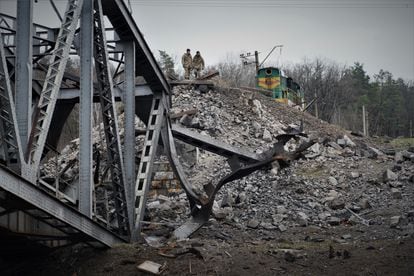 Two servicemen next to a railway bridge destroyed by a Russian attack in March.