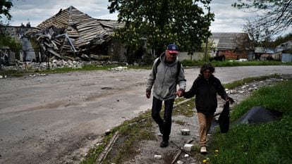 A couple walk past a bombed-out house in Kupiansk.