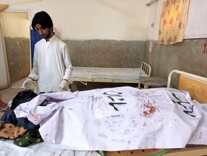 A paramedic stands beside a body of police officer, who was killed in a suicide bombing, in Sibi, a district in the Pakistan's Baluchistan province, on Monday, March 6, 2023.