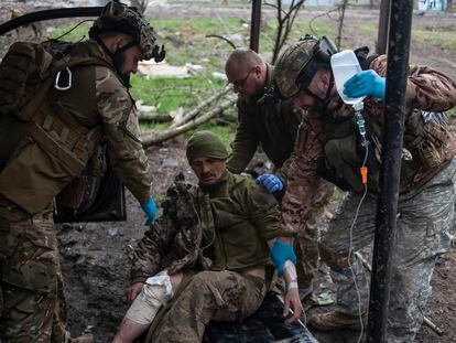 A Ukrainian soldier helps an injured colleague.