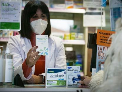 A pharmacist dispenses probiotics to a customer in an apothecary in Madrid.