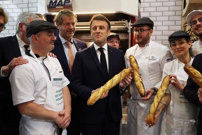 French President Emmanuel Macron (C) poses with a baguette at the bakers stand during the International Agriculture Fair in Paris on February 25, 2023, on the first day of the 59th edition of the fair.