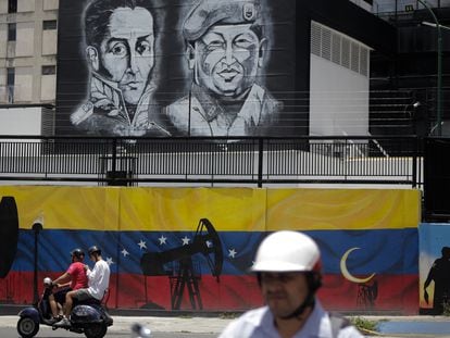 A motorcycle passes in front of a mural of Simón Bolívar and Hugo Chávez in Caracas, in an image from 2022.