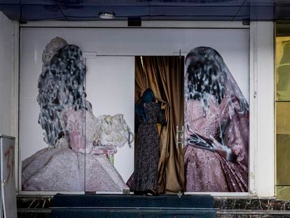 A woman enters a beauty salon in Kabul, whose promotional posters have been covered with paint to hide the faces of the women in them, on September 11, 2021.