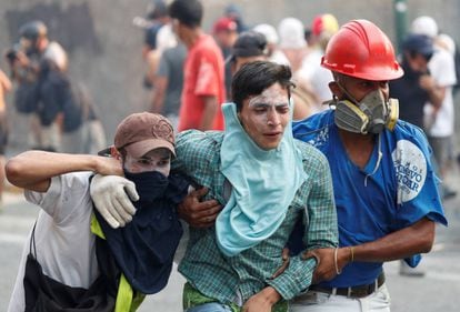 An injured demonstrator is assisted by others during clashes with government security forces in Caracas on Tuesday.