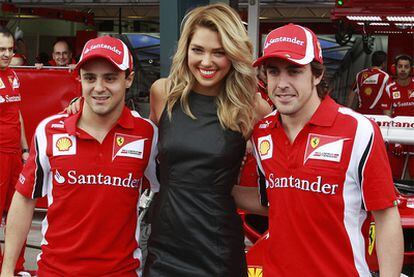Ferrari drivers Felipe Massa (l) and Fernando Alonso pose with Canadian model Ashley Hart in the paddock in Melbourne.