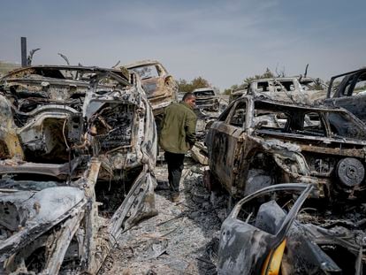 A Palestinian man walks between scorched cars in the town of Hawara, near the West Bank city of Nablus, on Monday, February 27, 2023.