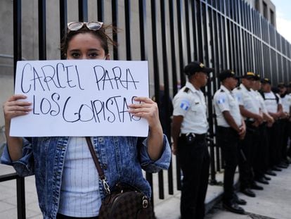 A protester holds a sign calling for those behind the decision to block Bernardo Arévalo's party from the elections to be jailed outside the Public Ministry in Guatemala City.