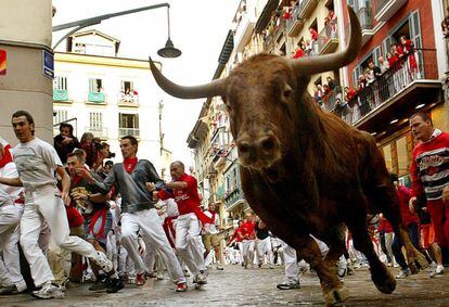 Runners and bulls take the corner on Estafeta street during the sixth day of the fiestas in 2004.