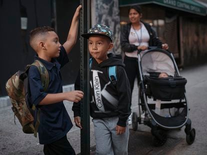 Kimberly Carchipulla, right, and her son 5-year-old Damien, center, wait for the bus on their way to school on Thursday, Sept. 7, 2023, in New York