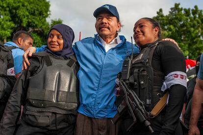 The president of NIcaragua, Daniel Ortega, poses with two police officers.