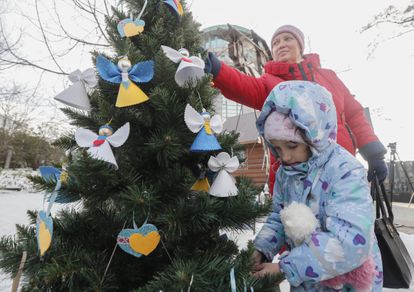 A woman and girl decorate a Christmas tree in Kyiv on December 23, 2022.