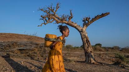 A young woman who fled the conflict in Ethiopia's Tigray region carries water at Umm Rakouba refugee camp in Qadarif, eastern Sudan.