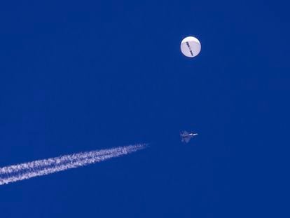 In this photo provided by Chad Fish, a large balloon drifts above the Atlantic Ocean, just off the coast of South Carolina, with a fighter jet and its contrail seen below it, Saturday, Feb. 4, 2023.