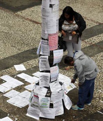 Two people read job postings on a street in São Paulo, Brazil.