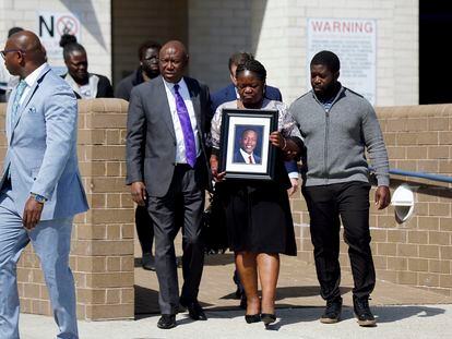 Caroline Ouko, mother of Irvo Otieno, holds a portrait of her son as she walks out of the Dinwiddie Courthouse with attorney Ben Crump, center left, and her older son, Leon Ochieng, in Dinwiddie, Va., on Thursday, March 16, 2023.