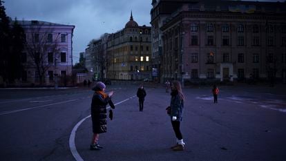 People walk and take photos on a street closed for cars at dusk in Kyiv, Ukraine, Sunday, Nov. 26, 2023.