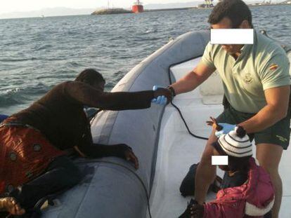 A Civil Guard officer helps a migrant aboard a patrol boat in Spanish waters. 