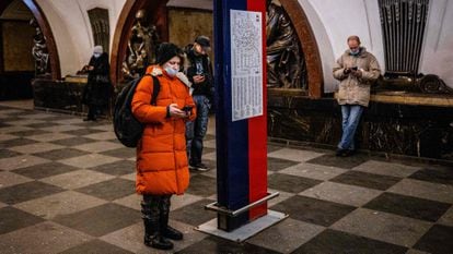 Commuters use their mobile phones at Ploschad Revolyutsii metro station in Moscow on March 10, 2021.