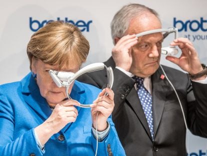 Former German Chancellor Angela Merkel and former Swiss President Johann Schneider-Ammann test augmented reality glasses at a technology fair in Hanover, Germany, in 2016.