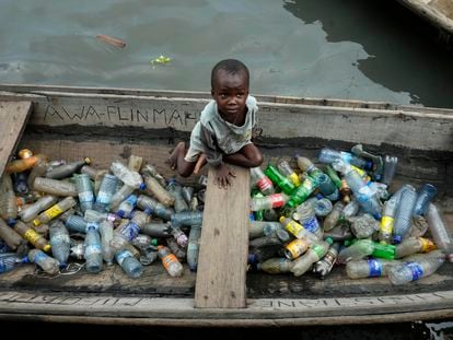 A child sits inside a canoe with empty plastic bottles he collected to sell for recycling in the floating slum of Makoko in Lagos, Nigeria, on November 8, 2022.