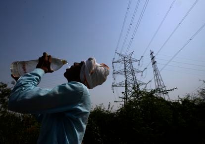A worker drinks water next to power lines during the heatwave in New Delhi, India.
