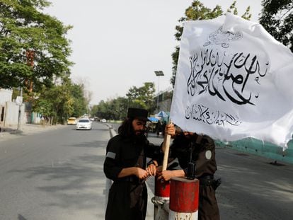 Taliban fighters plant their flag at a checkpoint in Kabul, July 21, 2022.