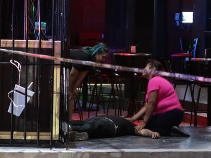 Two women with one of the victims of the shooting in a bar in Cancun, this Friday.
