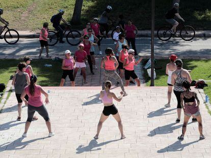 A group of women practices Zumba in a park.
