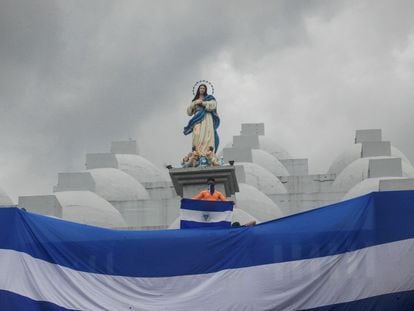 A young man holds a Nicaraguan flag on the rooftop of a cathedral during a protest.