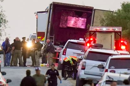 Police officers and first responders stand next to the trailer in which 53 migrants died, in San Antonio.