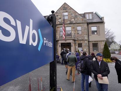 Customers and bystanders form a line outside a Silicon Valley Bank branch location, on March 13, 2023, in Wellesley, Massachusetts.