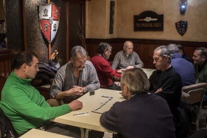 Pensioners in Ciñera, León, play dominoes in a bar.