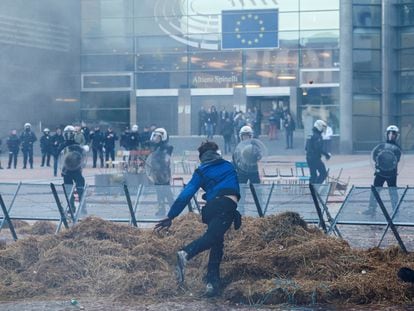 A demonstrator throws an object towards police officers in riot gear outside the European Parliament as farmers from European countries protest over price pressures, taxes and green regulation, in Brussels, Belgium February 1, 2024.