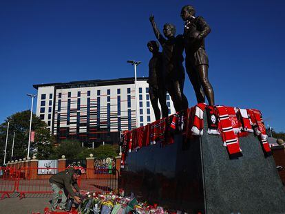 A fan lays flowers down in front of the George Best, Denis Law and Bobby Charlton statue outside Old Trafford, October 22, 2023.