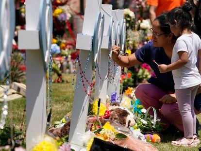 A woman signs a cross as a child looks on at a makeshift memorial by the mall where several people were killed in Saturday's mass shooting, on May 8, 2023, in Allen, Texas.