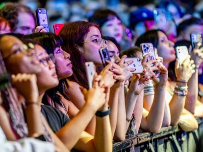 Teenagers use their phones while Alex G performs during a concert in New York.