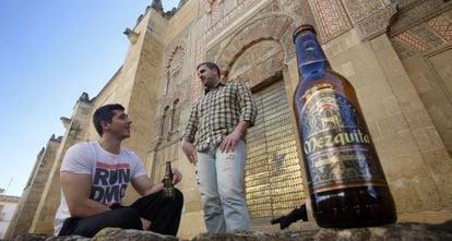 Two people drink Mezquita beer in front of the Córdoba monument.