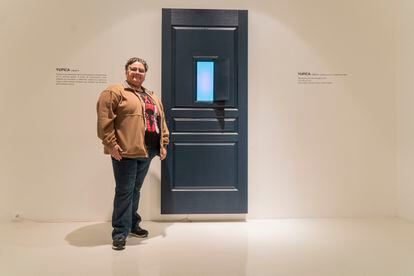 Ángel Trompiz, a trans man from Venezuela, stands next to a piece by the artist Yupica at the 'Doors of Hope' exhibition.