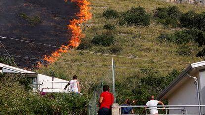 Residents look at flames burning in Capaci, near Palermo, in Sicily, southern Italy, Wednesday, July 26, 2023. 